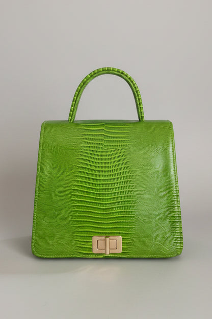 A bright lime green crocodile-embossed leather handbag with a top handle and a gold-tone clasp, displayed on a white marble surface.
