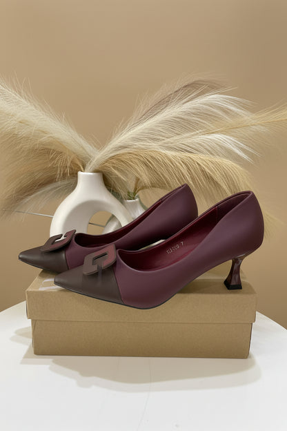 A pair of pointed-toe heeled pumps in a deep burgundy color, featuring a decorative square buckle detail on the toe box. 